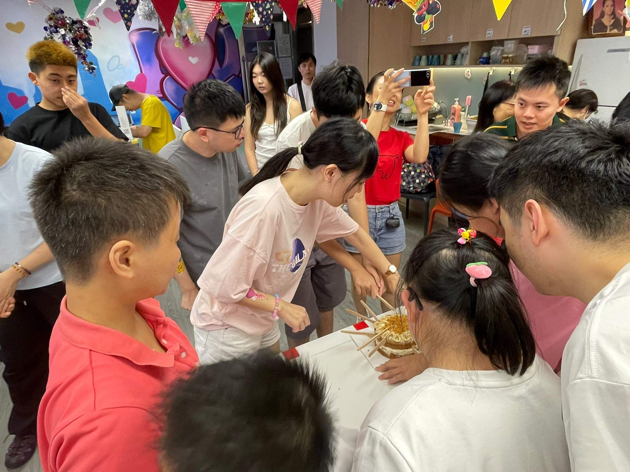 The group gathers as a cake is prepared for sharing.