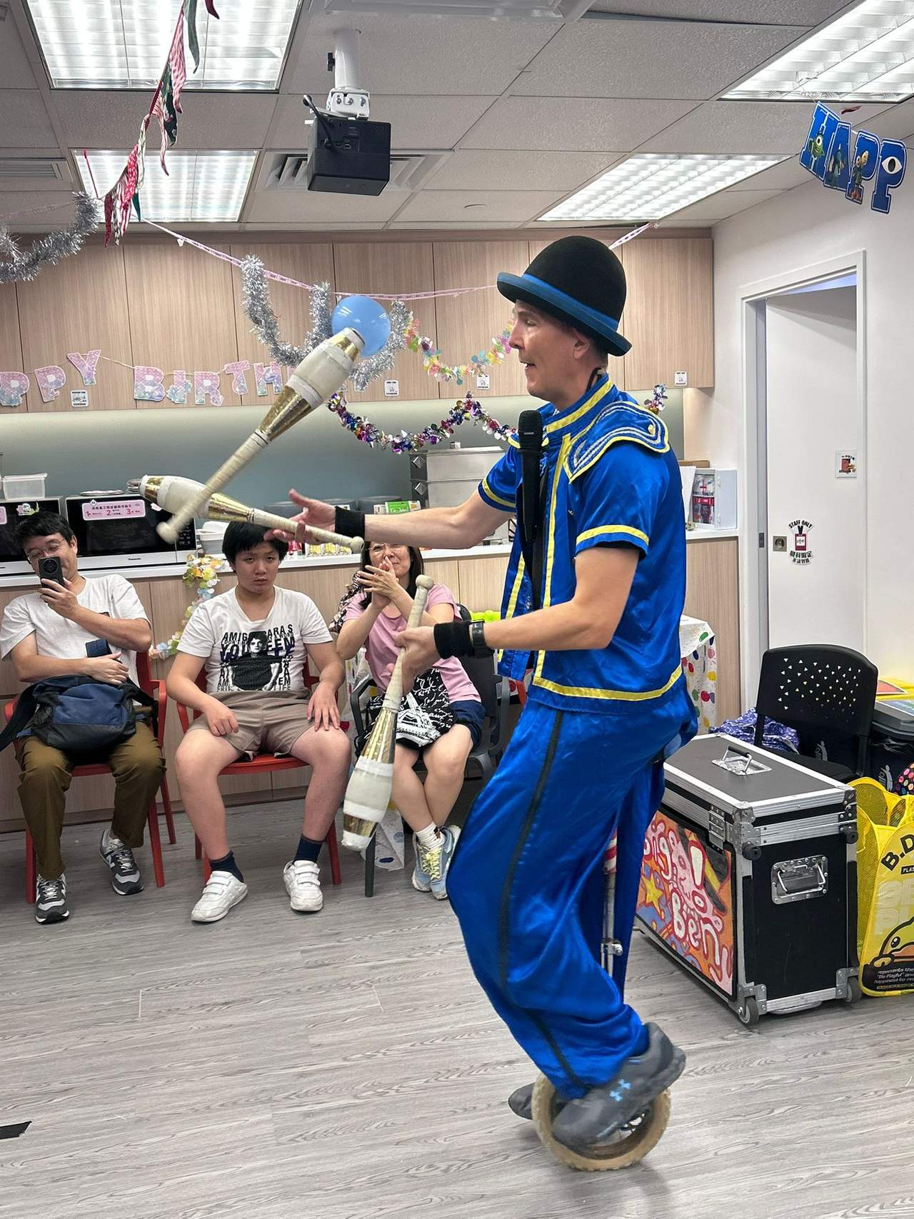 A performer juggles clubs in front of the seated group.