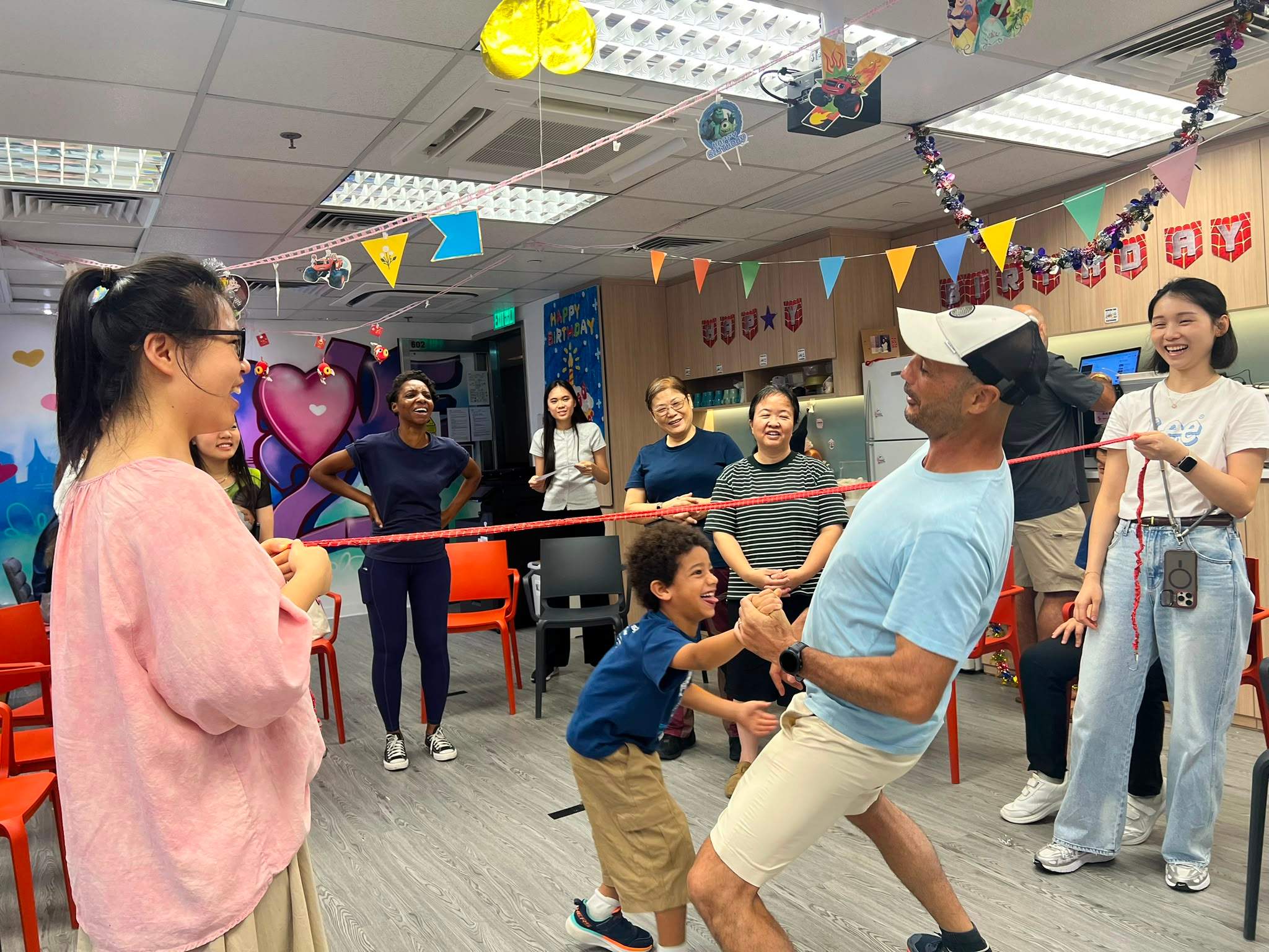 A child ducks beneath a limbo bar while people watch.