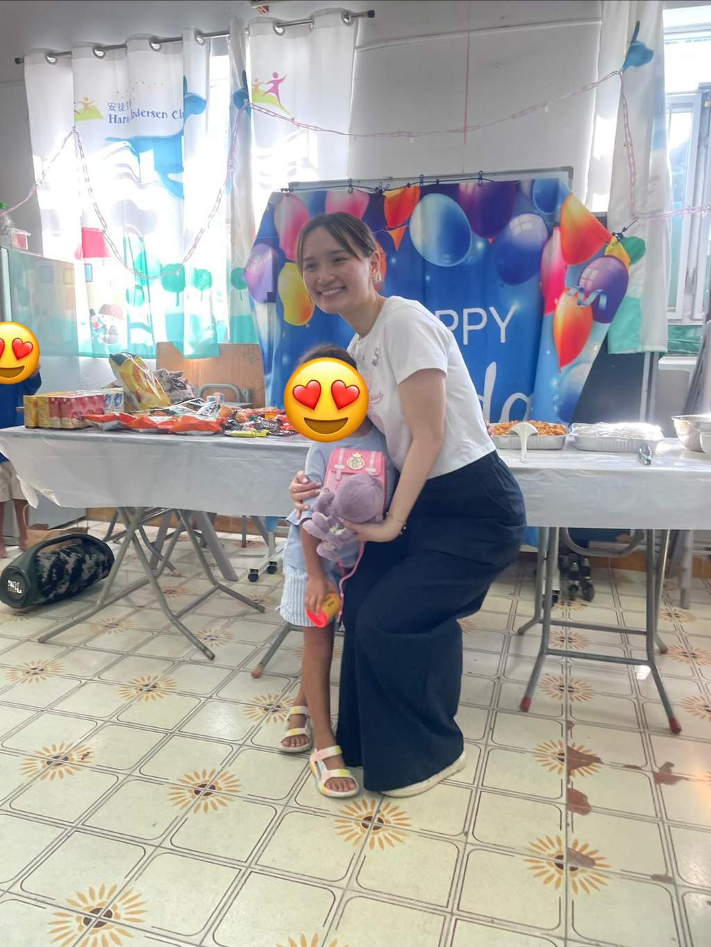 An adult and child pose together before a balloon backdrop.