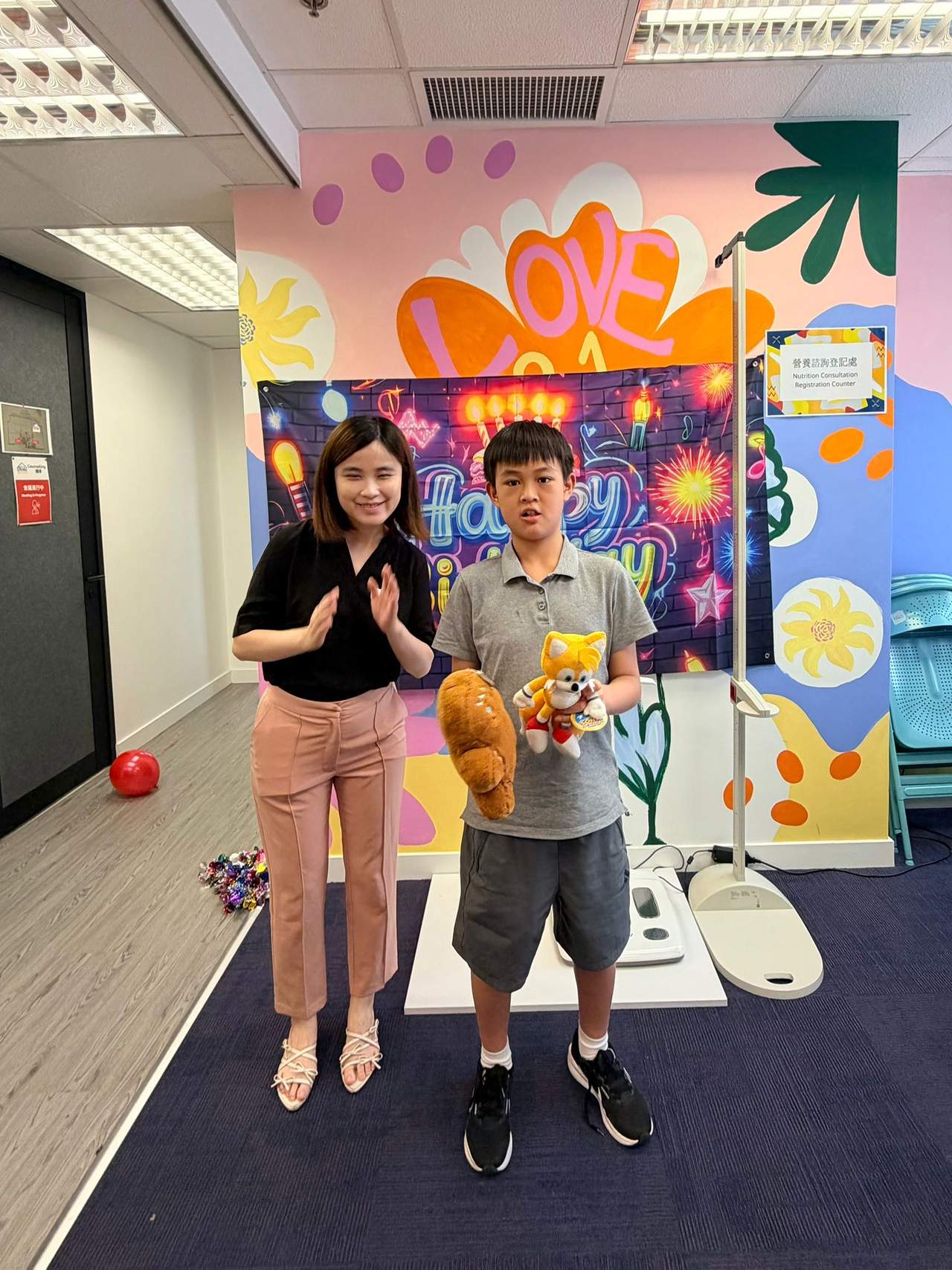 Two people stand together with stuffed toys and a gift.