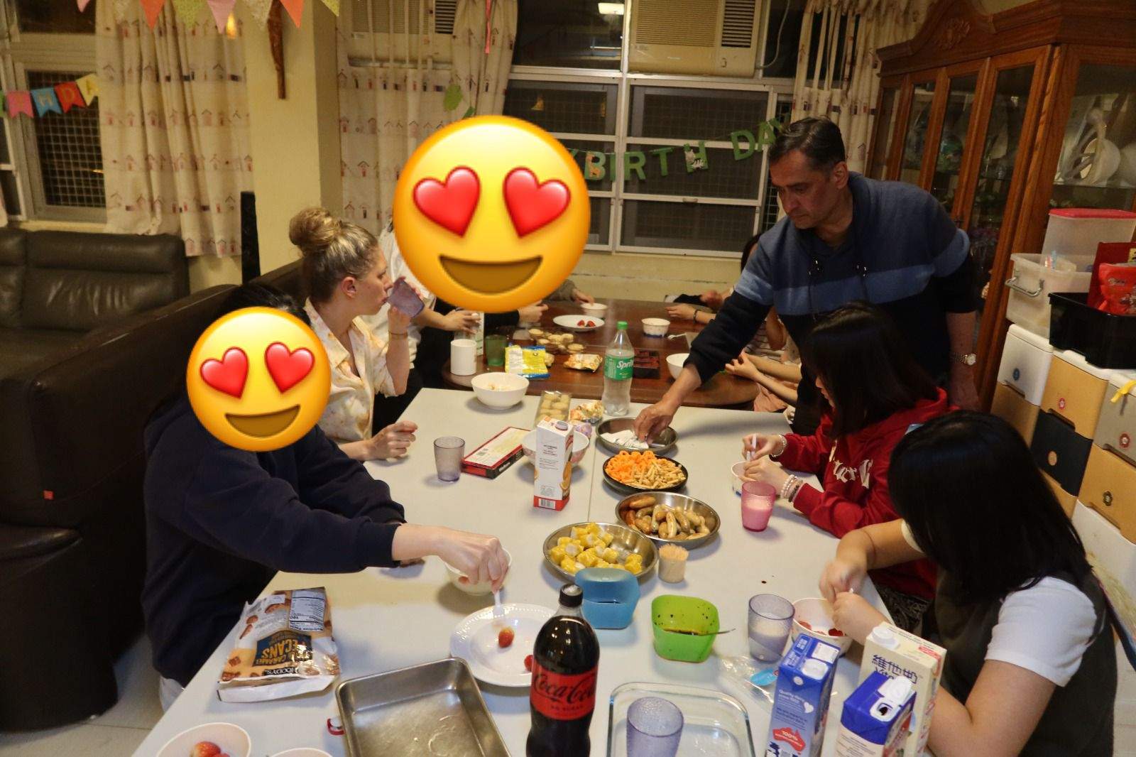 Adults and children share food around a crowded dining table.