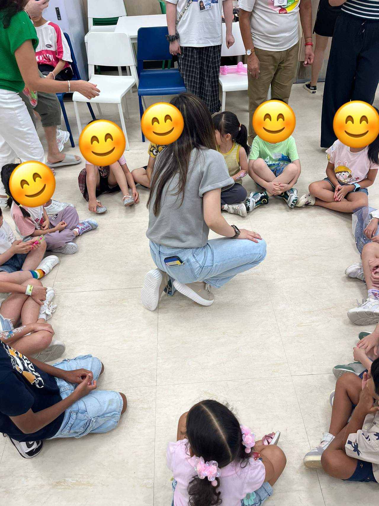 Children sit in a circle around an adult leading an activity.