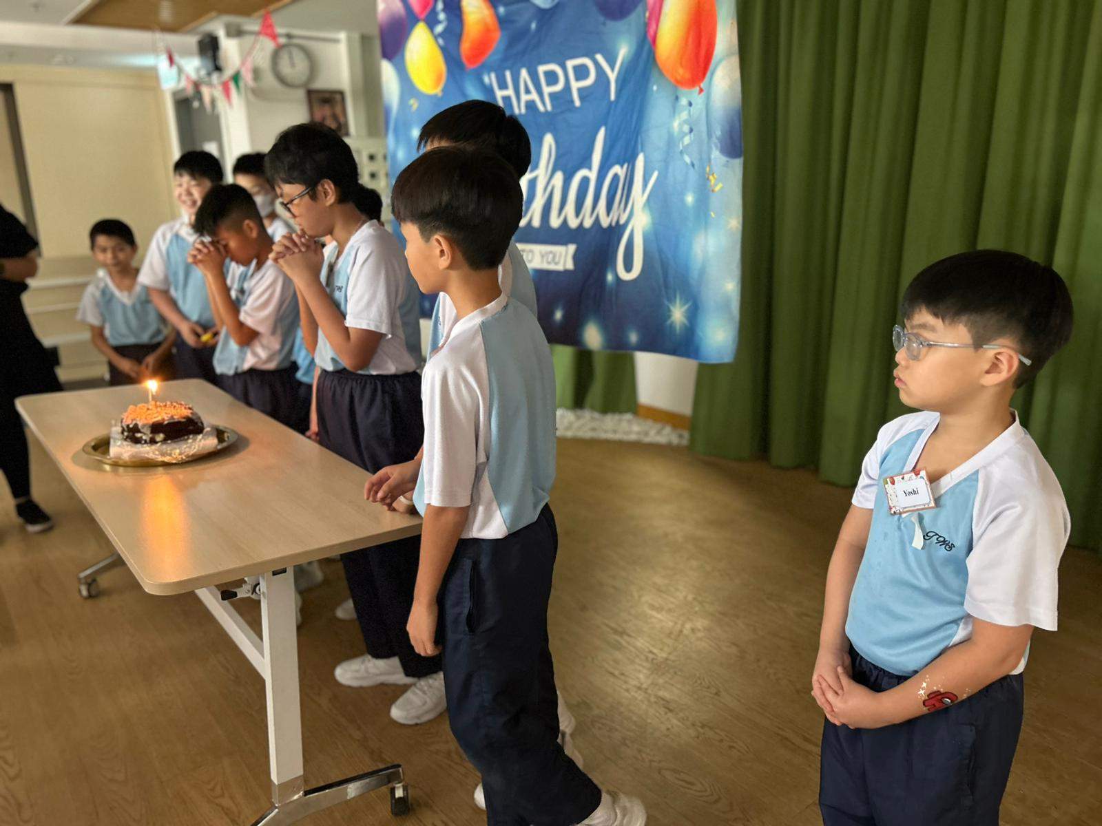 Children line up beside a cake with candles.
