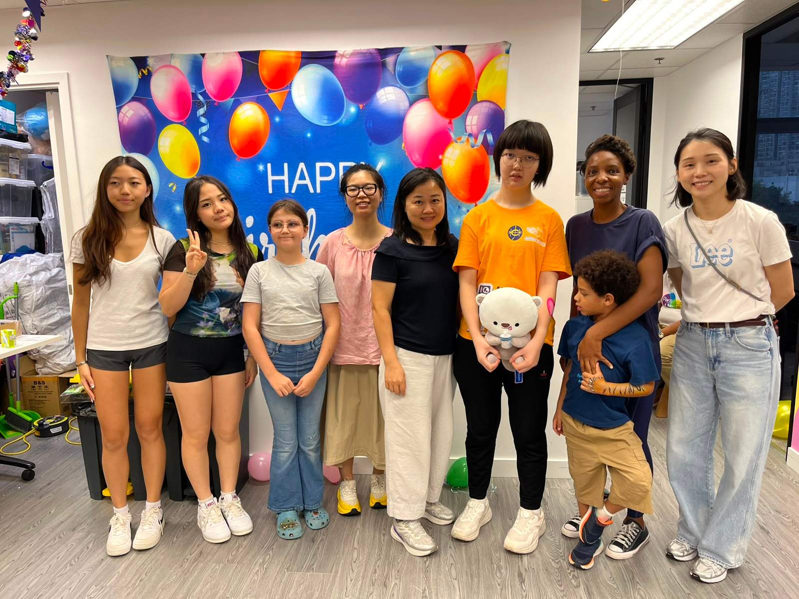 A group poses together in front of a balloon backdrop.