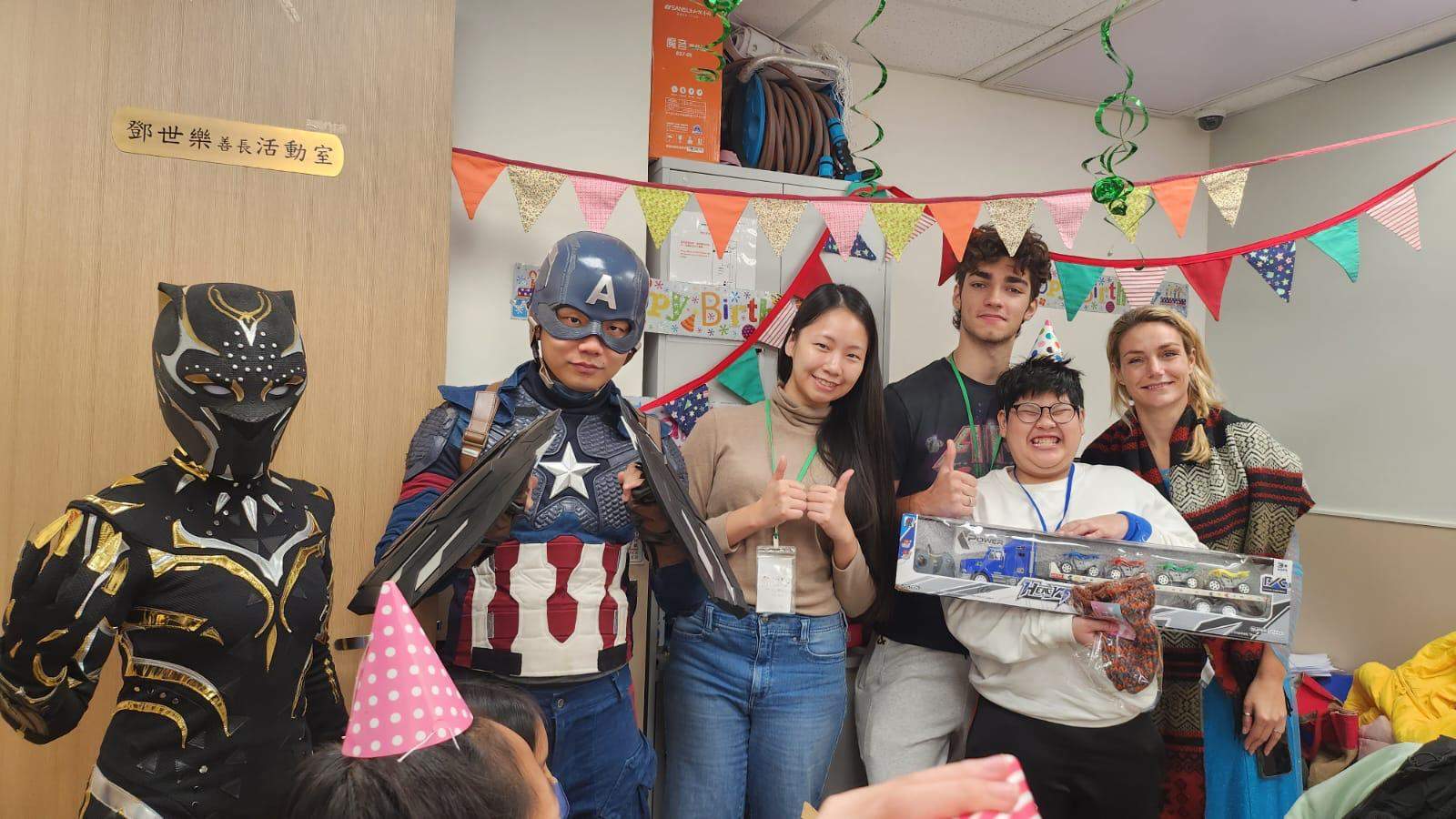 A delighted child receiving a gift from costumed Birthday Happiness Asia volunteers at a party.