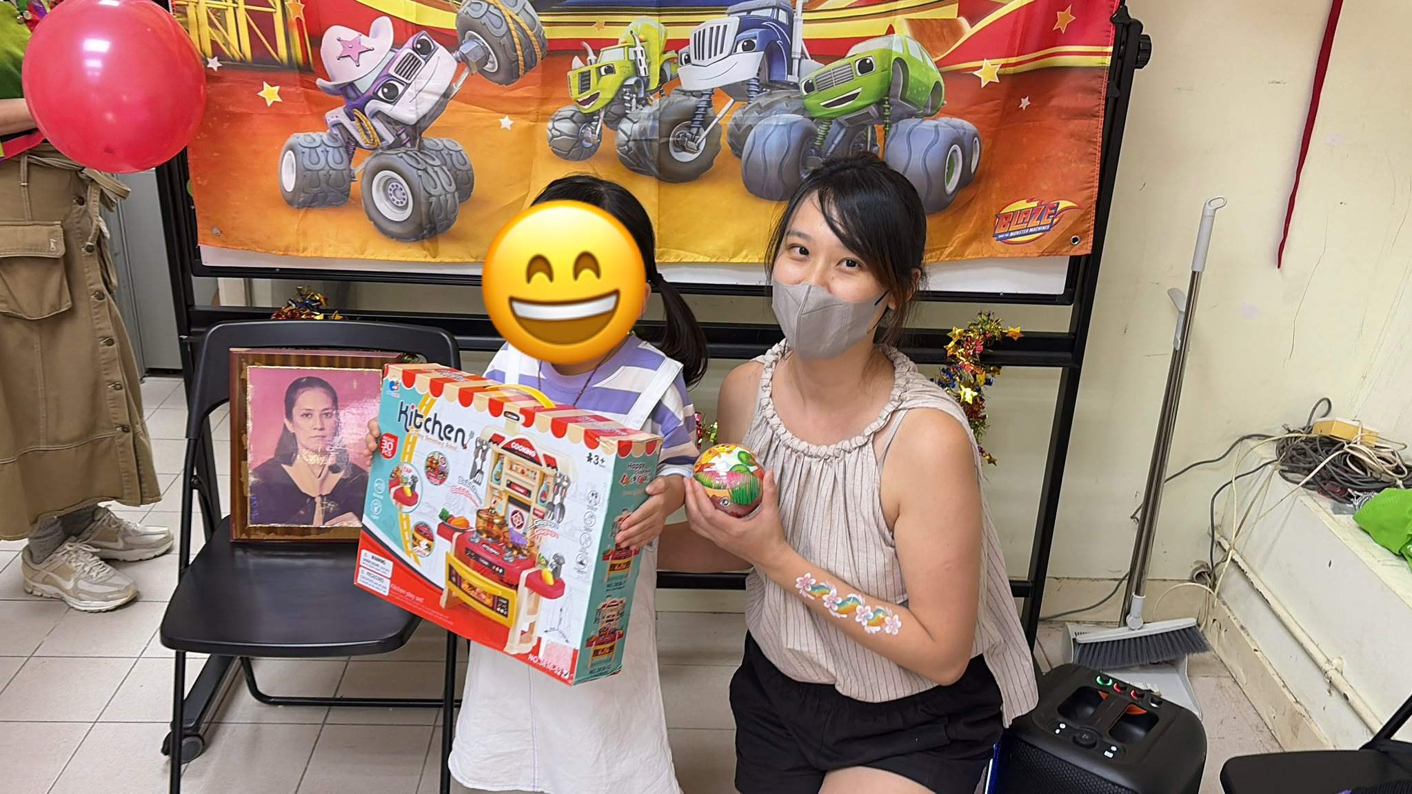 A child displays a play-kitchen gift beside a volunteer.