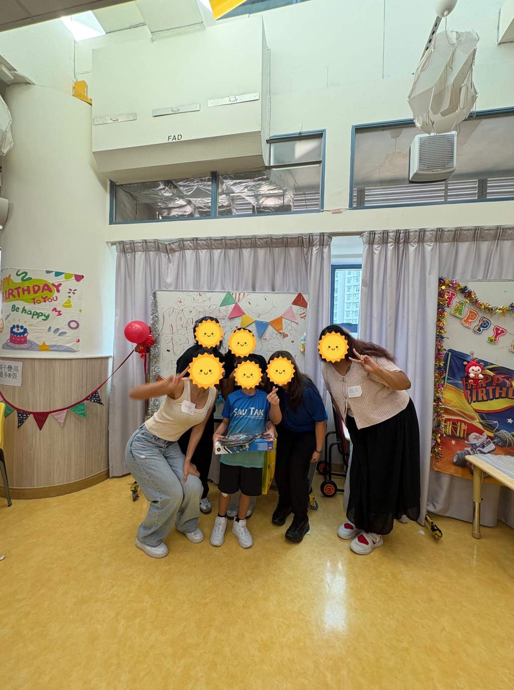 A child holding gifts with volunteers in front of birthday decorations.