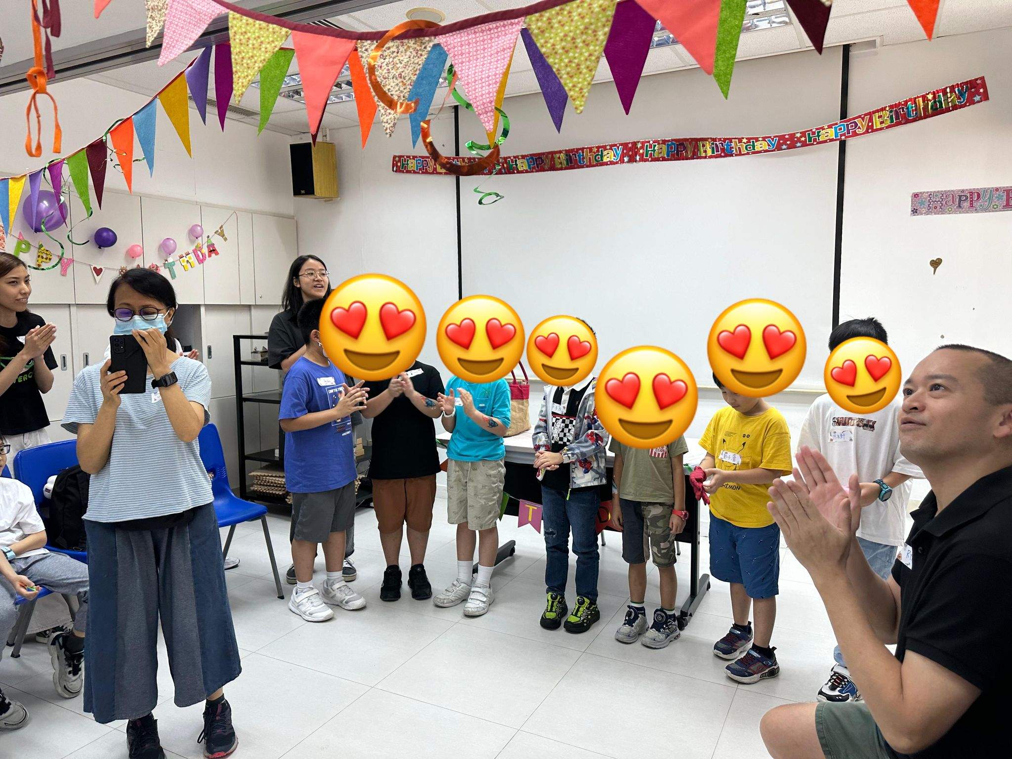 Children stand in a row while adults lead an activity.