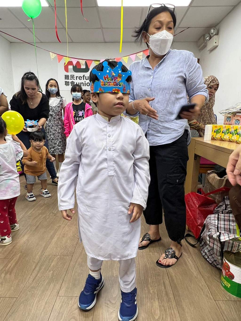 A blindfolded child stands while an adult guides a party game.