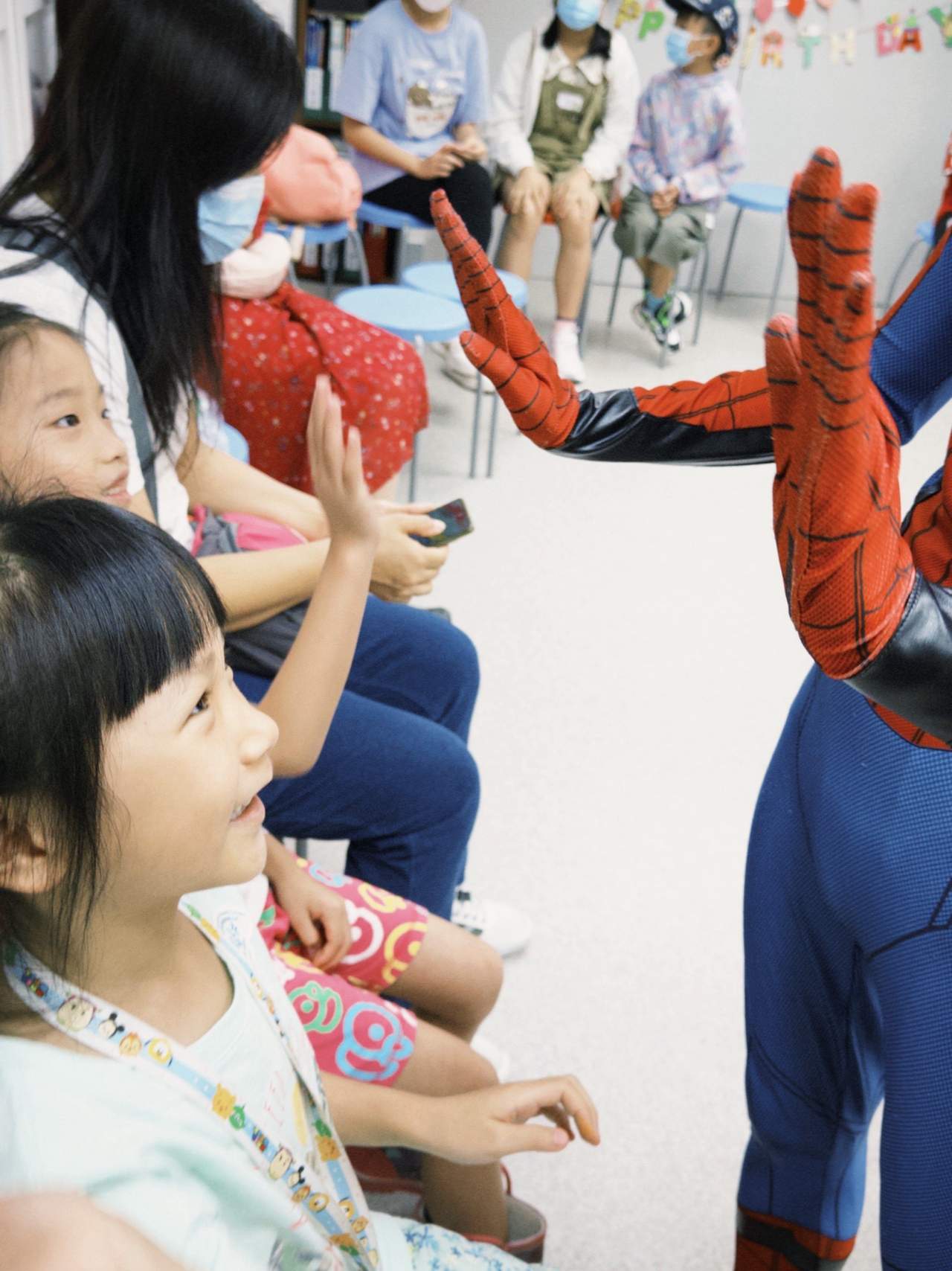 A costumed performer greets children seated in a row.