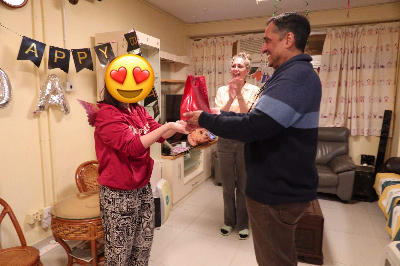 Two adults exchange a gift while another adult watches.