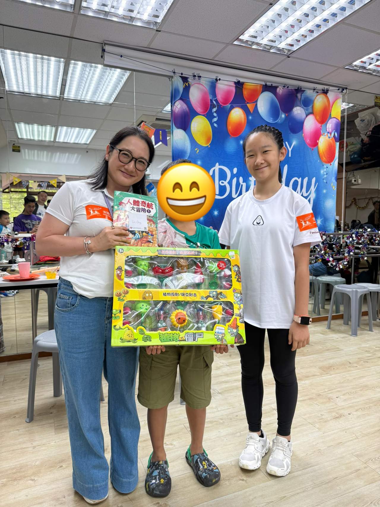 Two adults and a child display a large boxed toy.