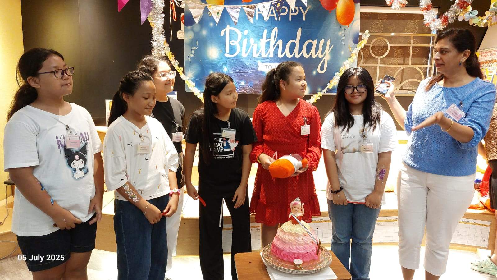 Adults and children gather around a decorated cake table.