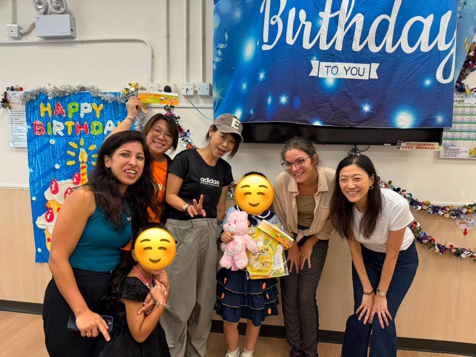 Volunteers and a child pose with birthday gifts.
