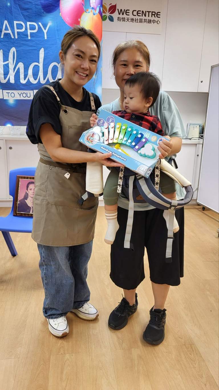 Two adults pose with a child holding a decorated cake.