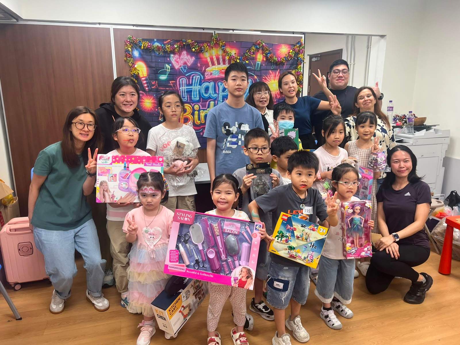 A large group poses together with toys and gift boxes.