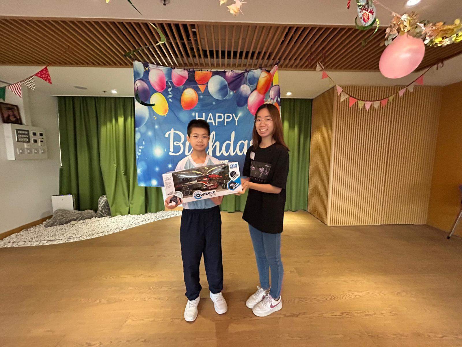 An adult and child pose together with a boxed gift.