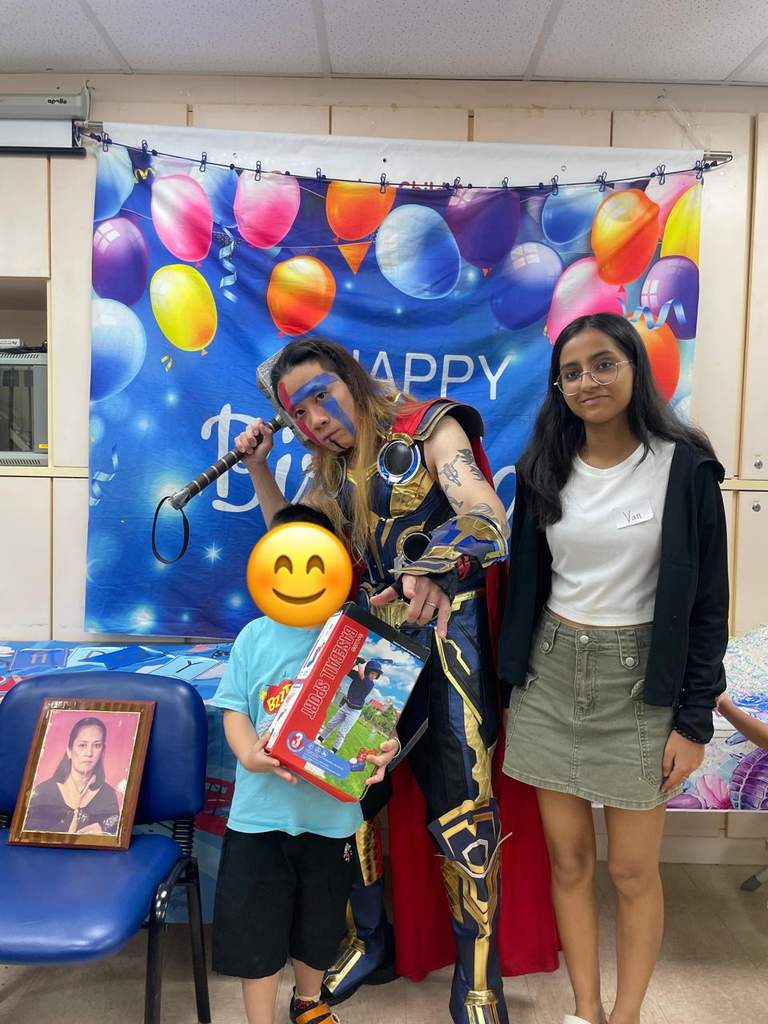 A costumed performer and adult pose with a child and gift.