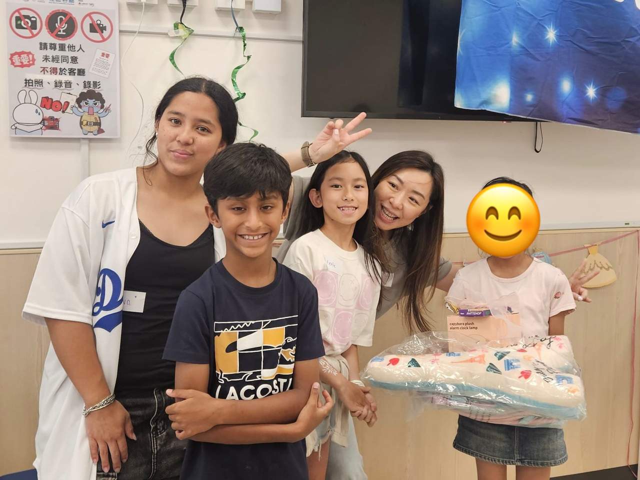 Adults and children pose together holding a large wrapped item.