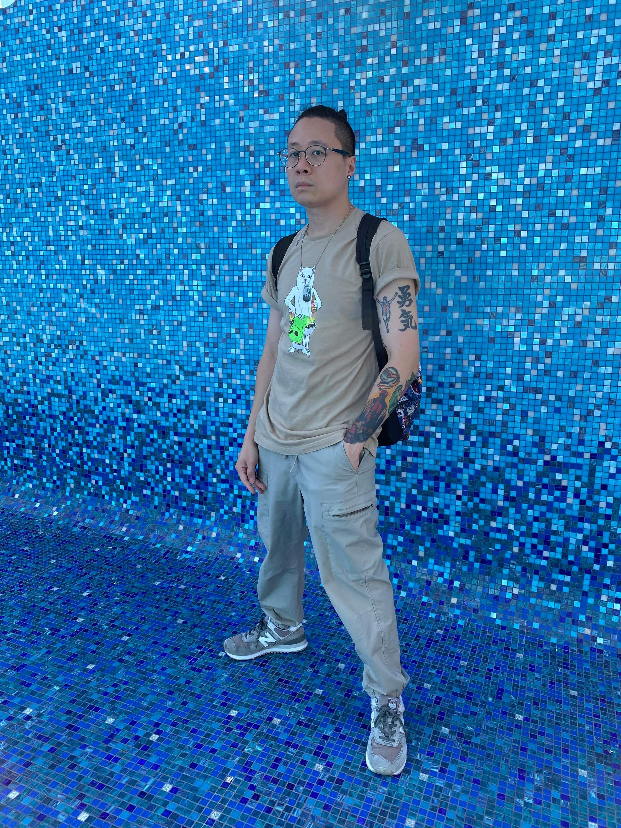 Kiryu Chan out of costume, against a blue mosaic wall.