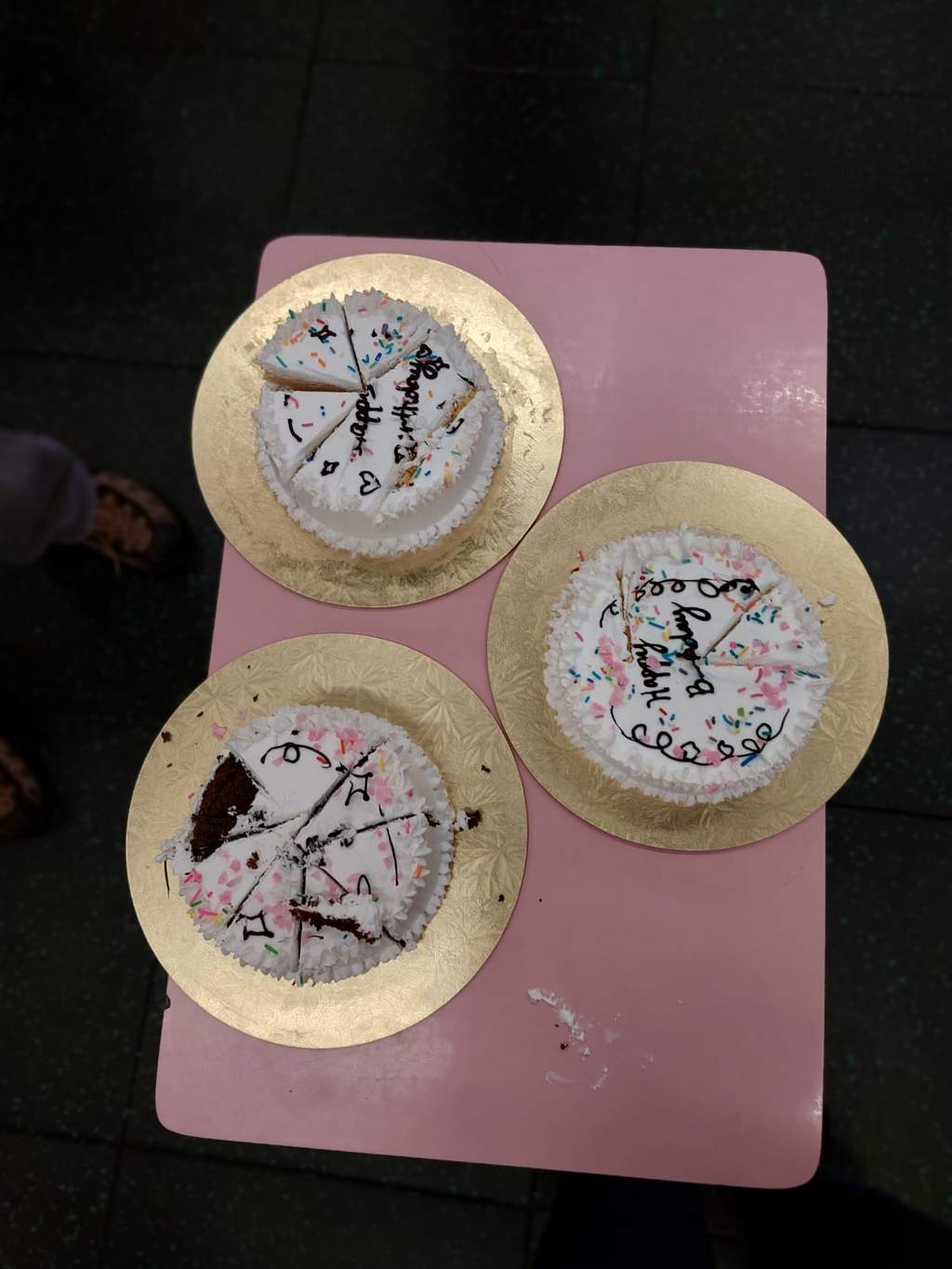 Three round decorated cakes sit together on a small table.