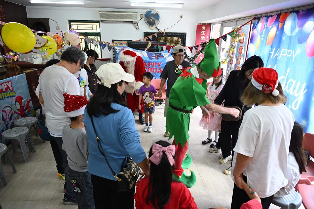 Children gather around two costumed performers beneath festive decorations.