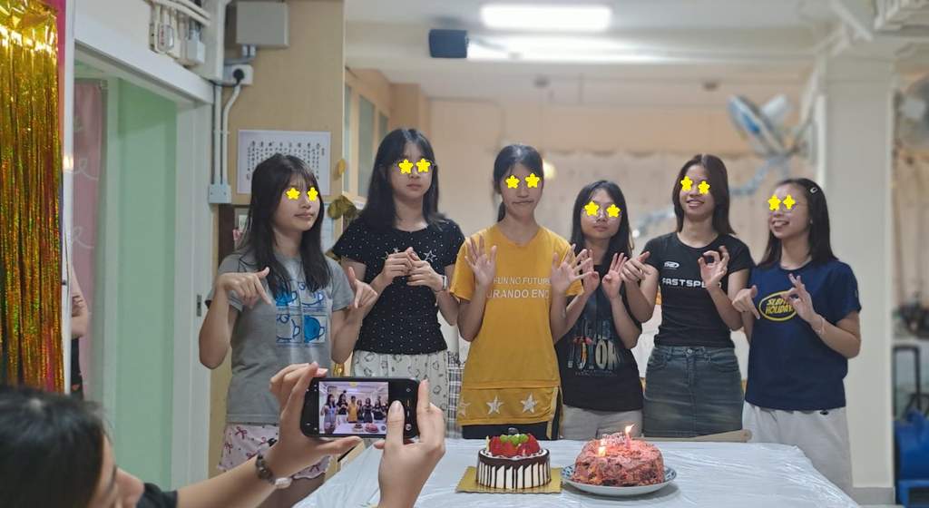 A group stands behind two cakes while someone photographs them.