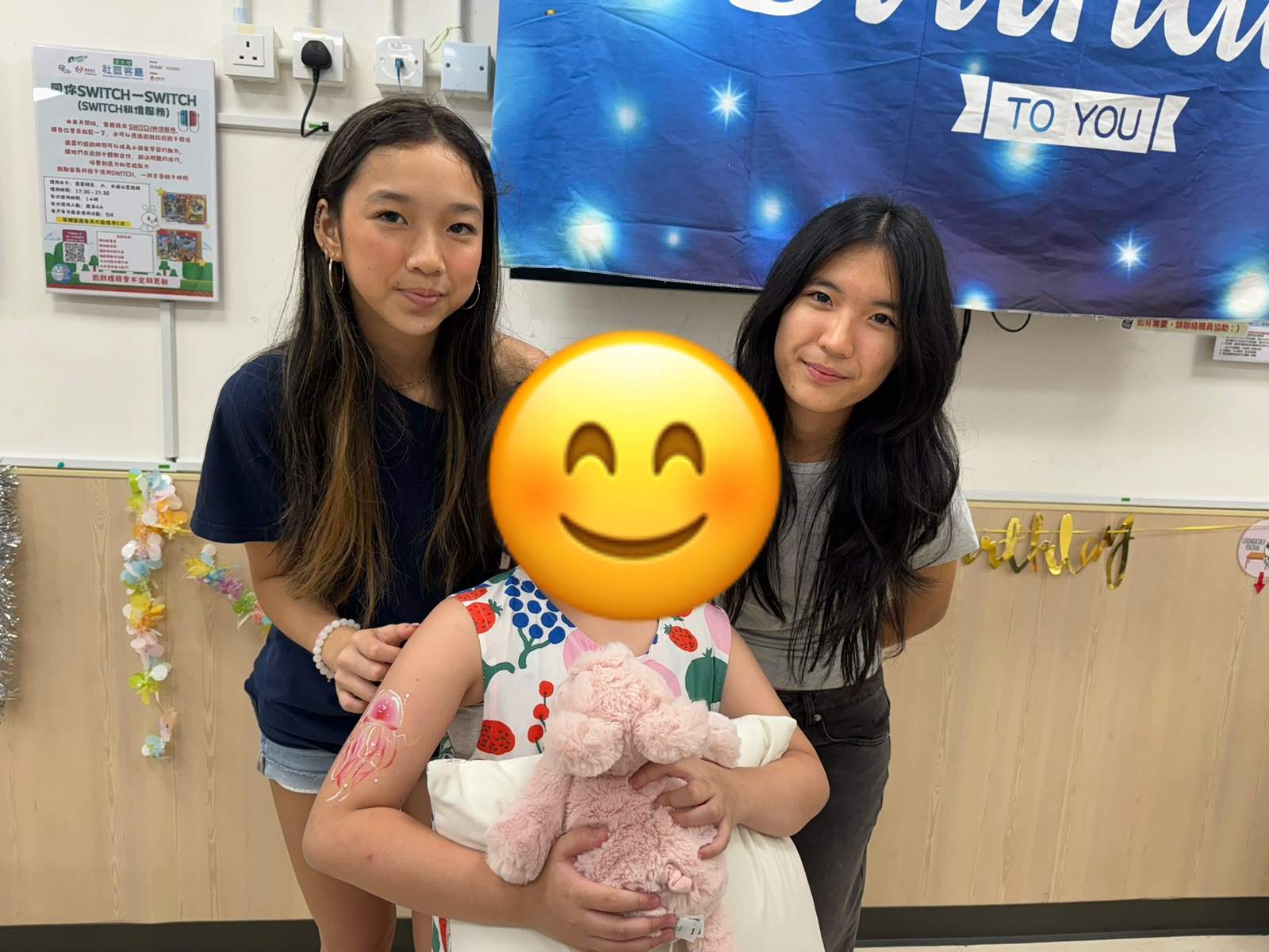 Two adults stand behind a child holding a stuffed animal.