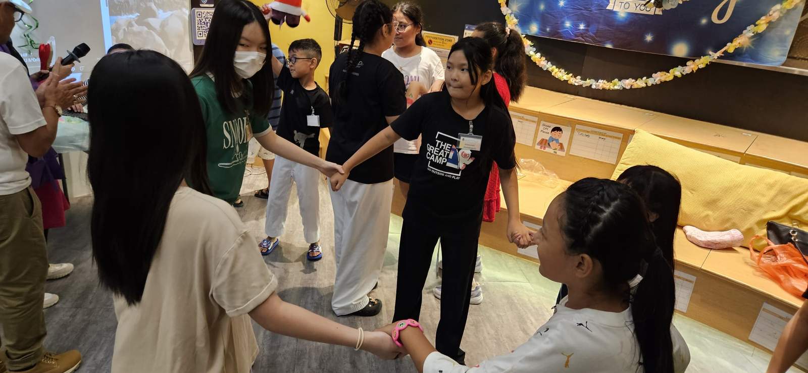 Children and adults hold hands in a circle activity.