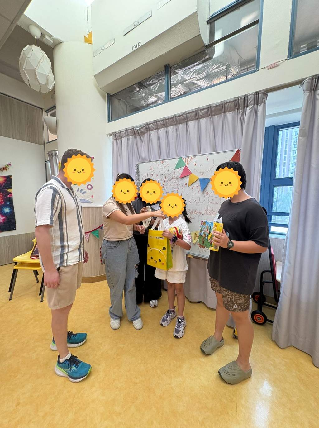 Volunteers and a child holding gifts beside the birthday decorations.