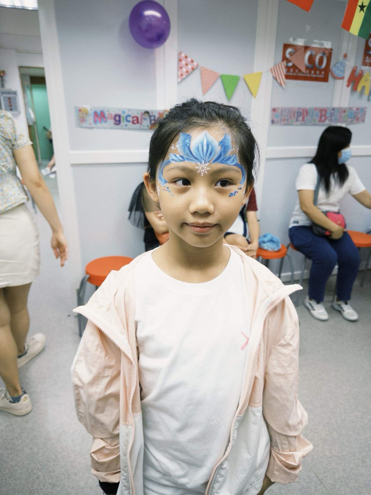 A child stands for a portrait with a painted face design.
