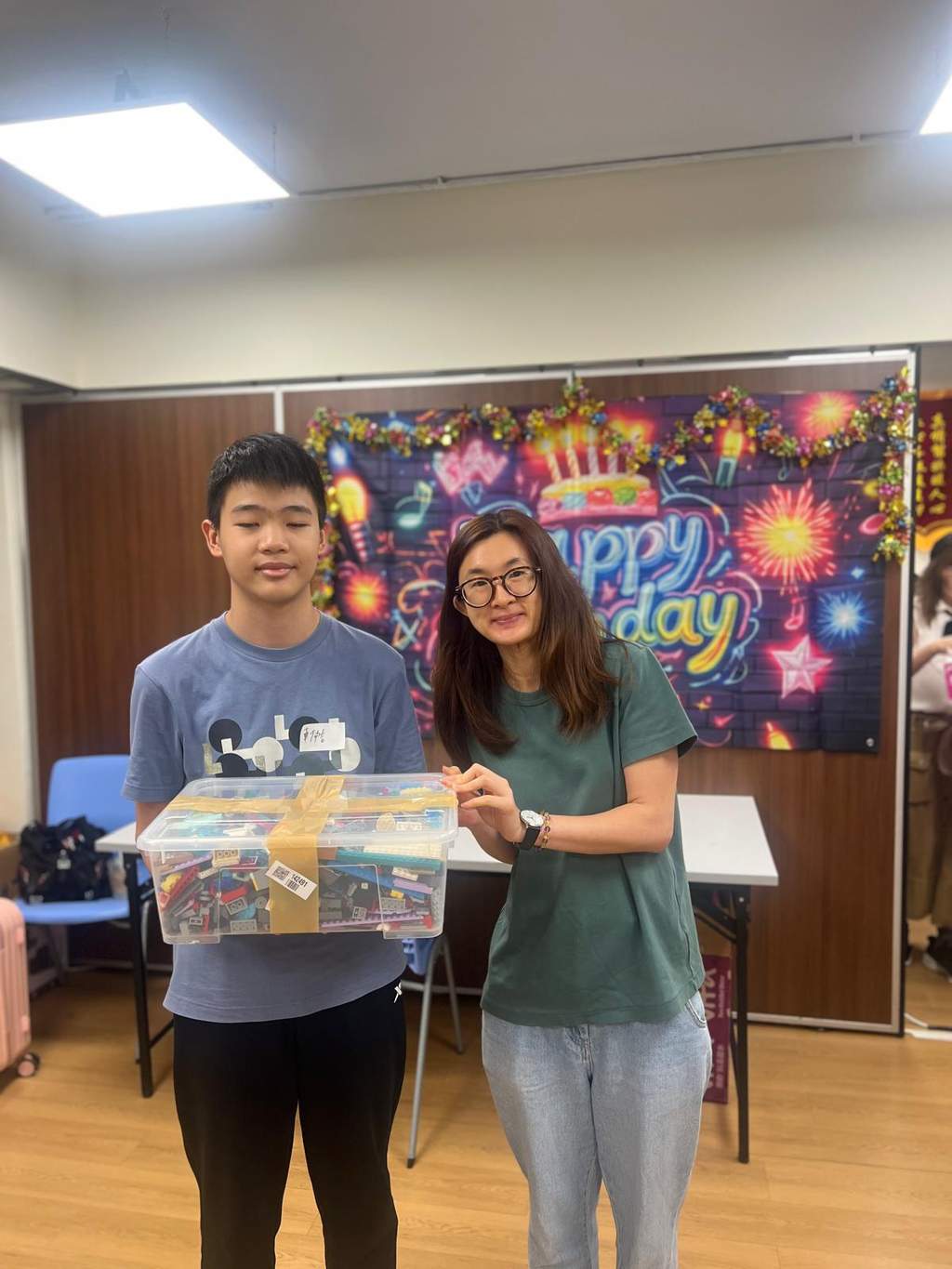 A child and adult hold a large boxed gift together.