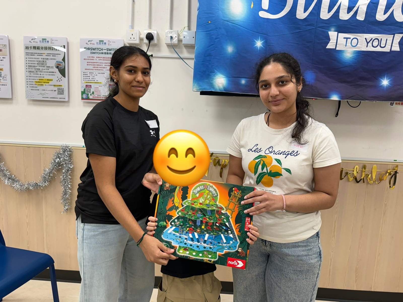 Two adults stand beside a child displaying a boxed toy.