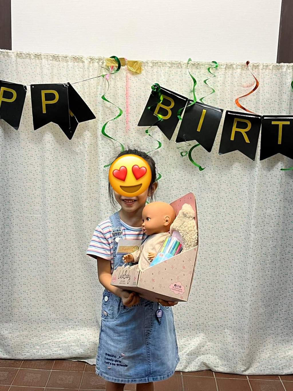 A child holds a gift bag beneath birthday bunting.