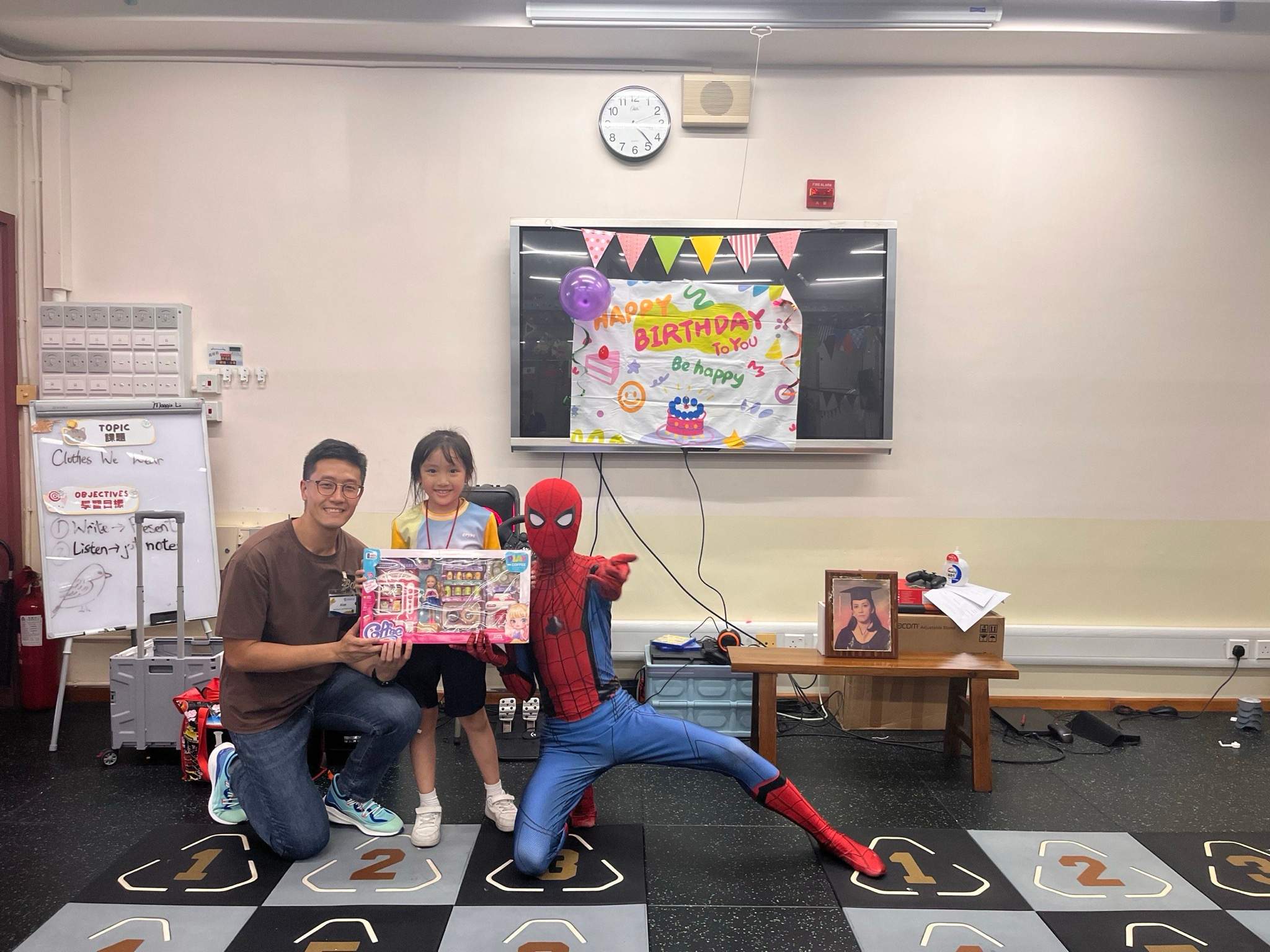 An adult and costumed performer pose with a child and boxed gift.