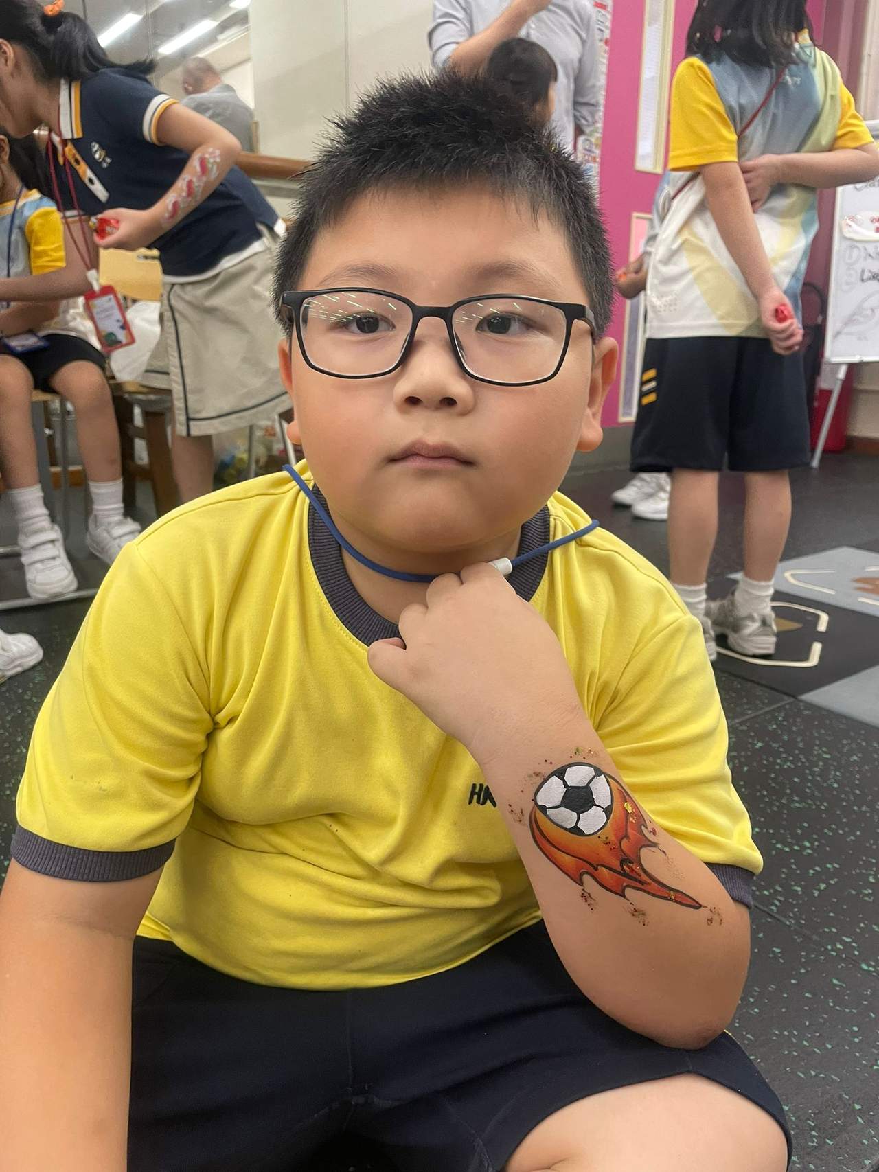 A seated child displays painted artwork on their forearm.