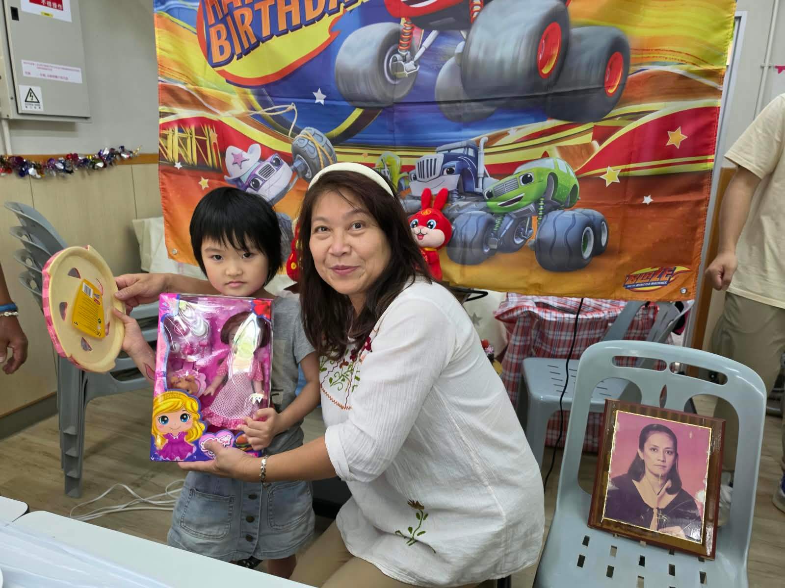 A child holds a doll gift beside a volunteer.