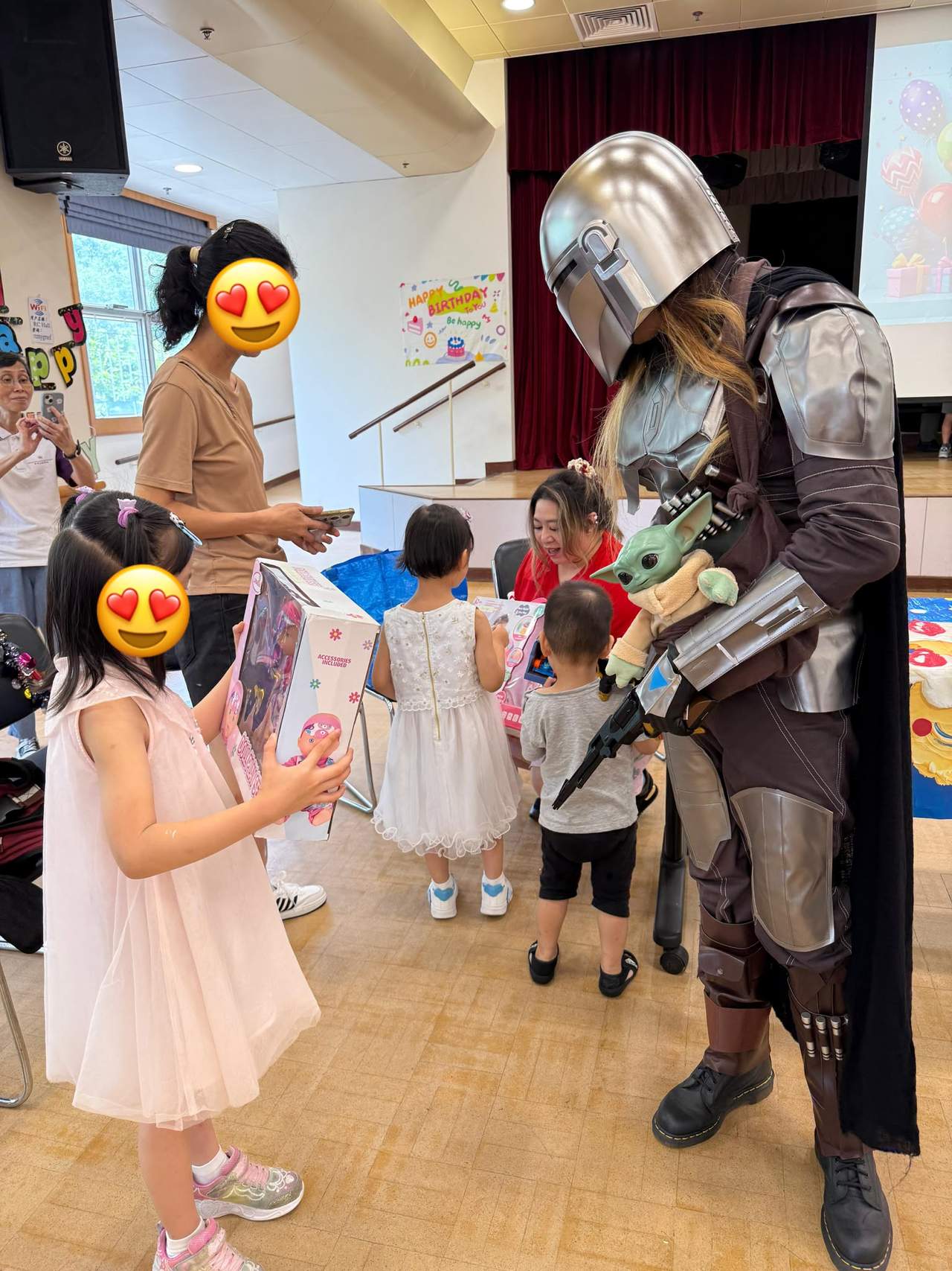 Adults hand party gifts to children gathered around them.