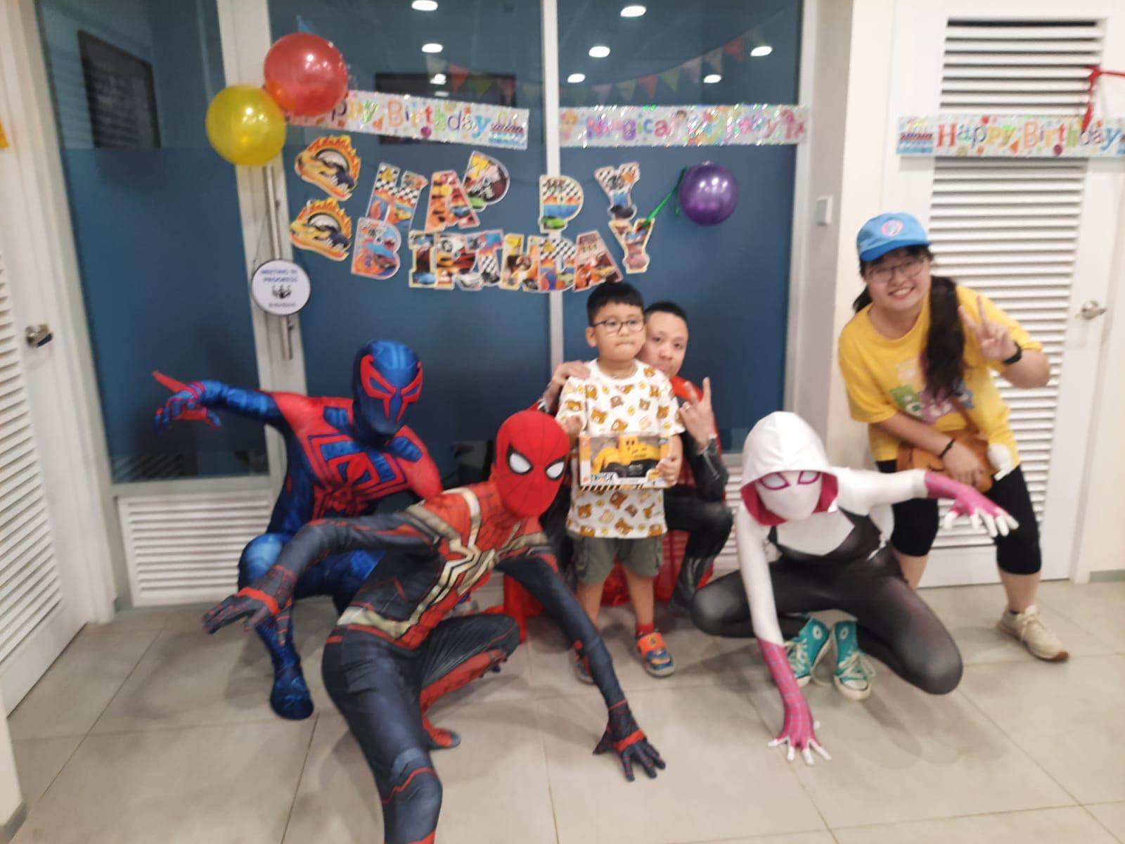 Costumed performers and an adult pose with a child holding a box.