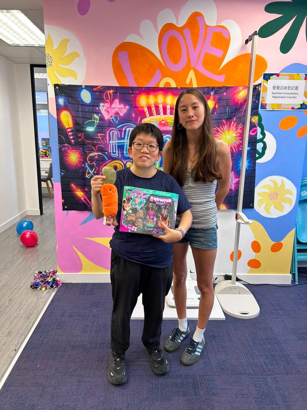Two people stand together displaying a boxed gift.