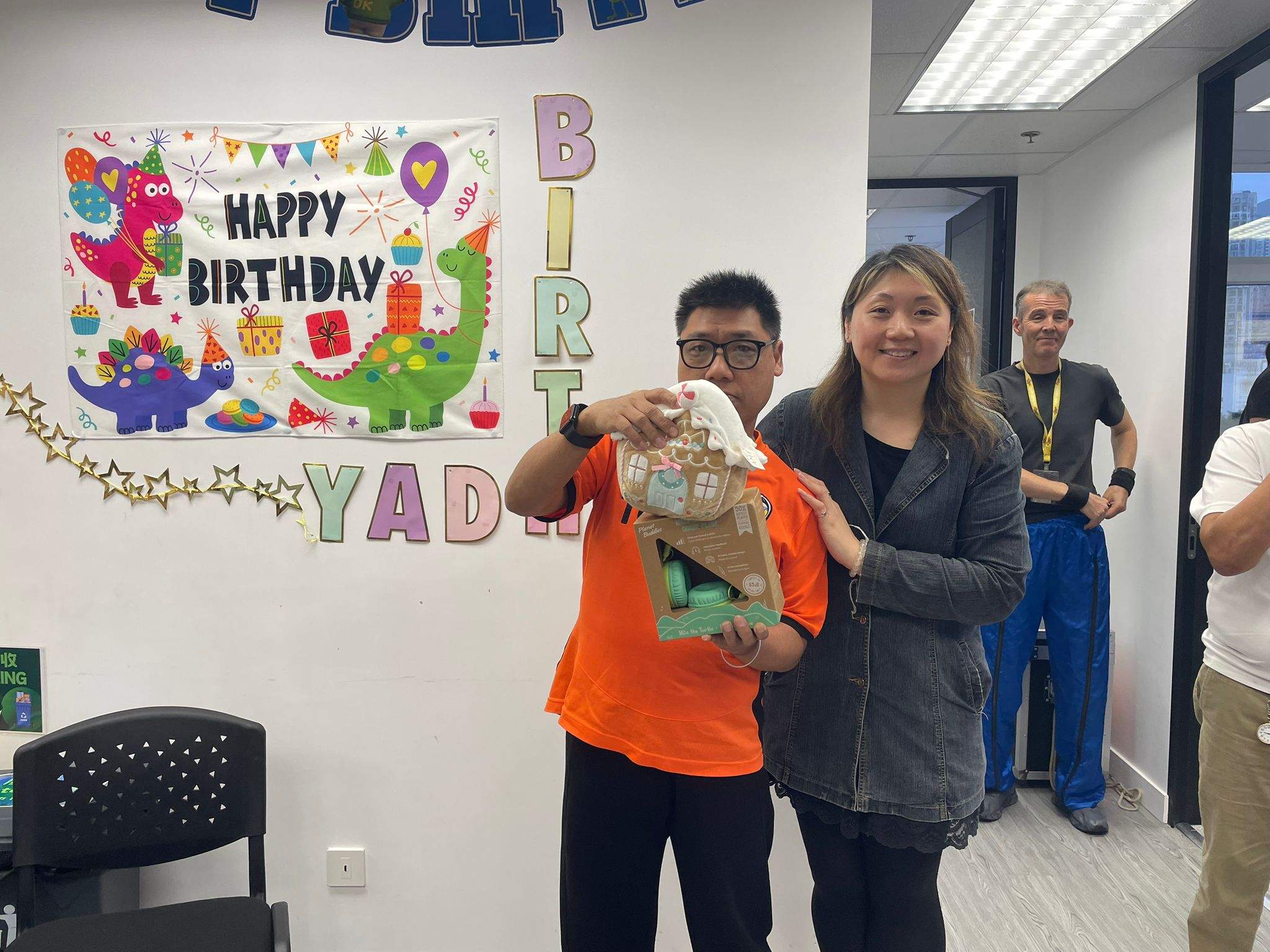 An adult stands beside a person holding a bag and gift.