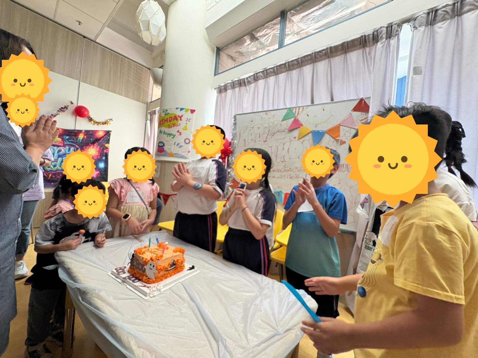 Children clapping around a birthday cake with lit candles.