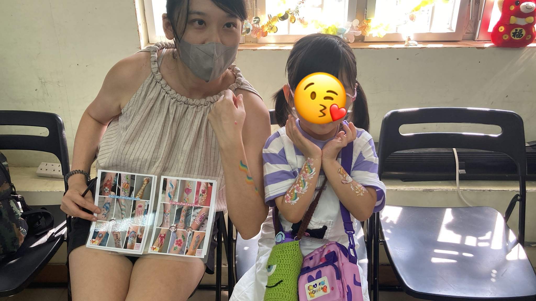 A child and face painter pose with painted arm designs.
