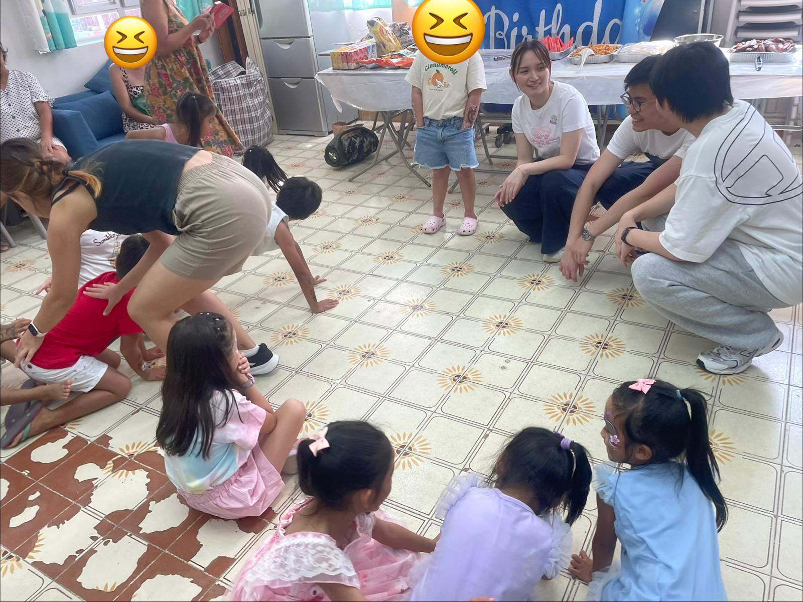 Children sit on the floor while adults lead an activity.