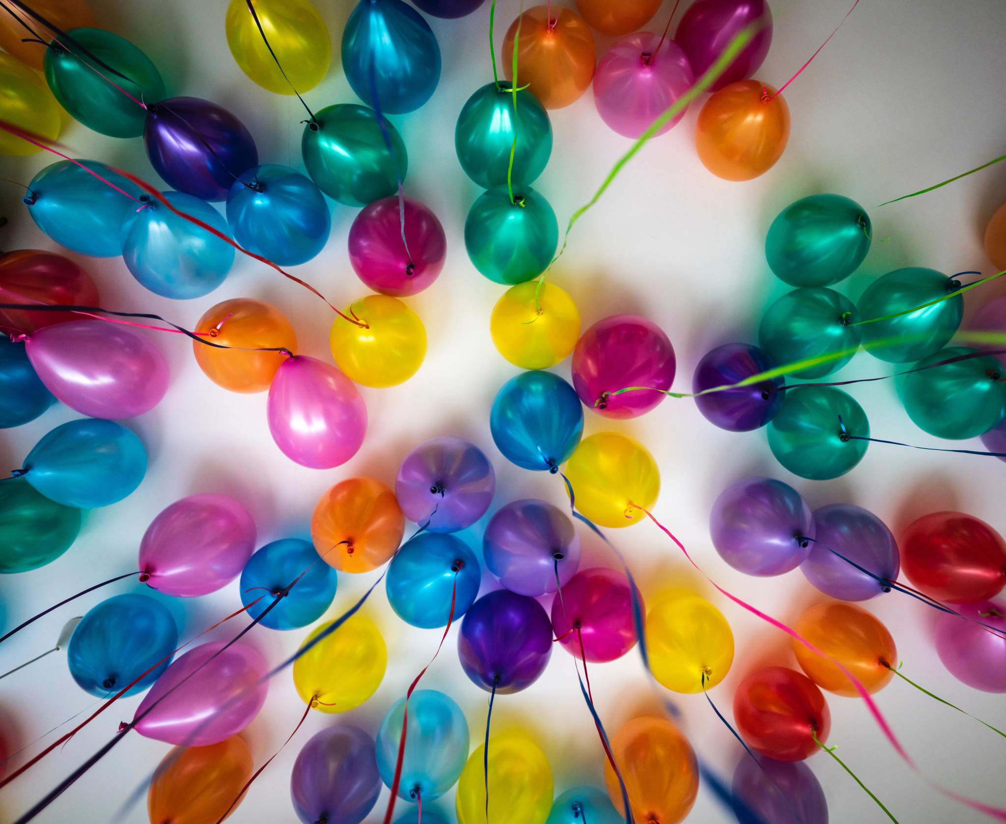 Colourful balloons and ribbons spread across a ceiling overhead.