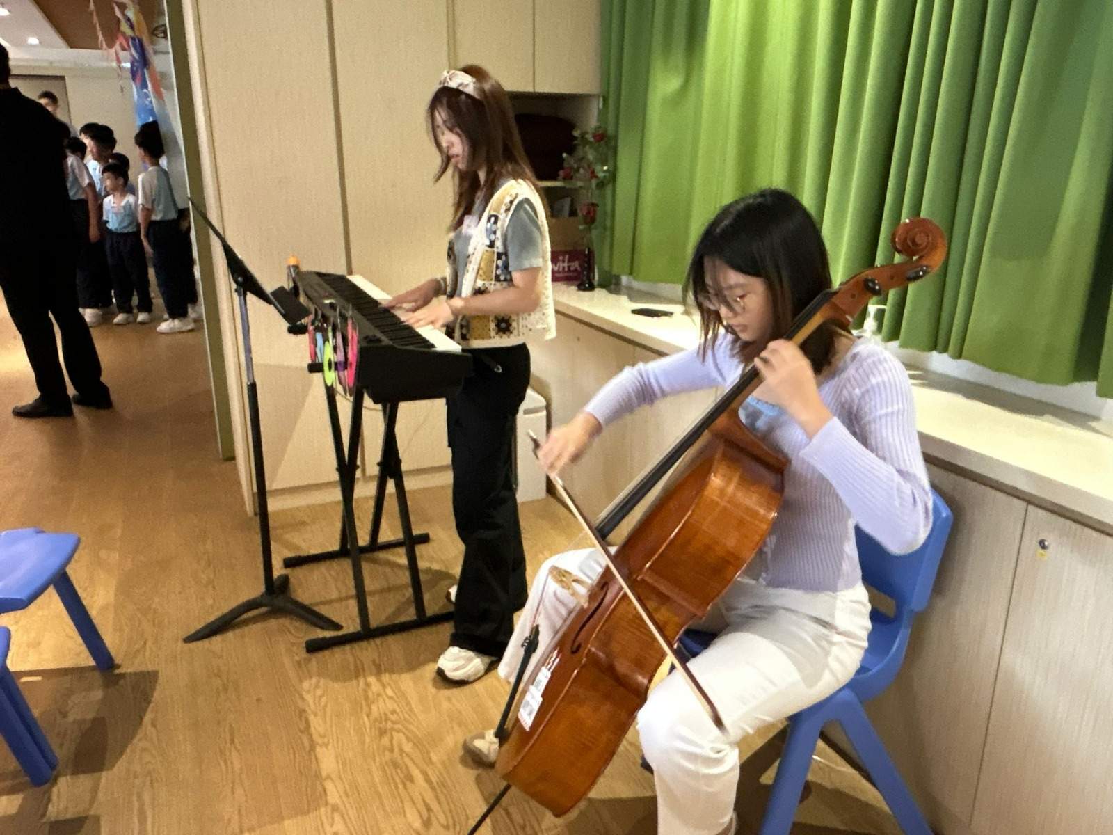 Two adults perform music with a keyboard and cello.