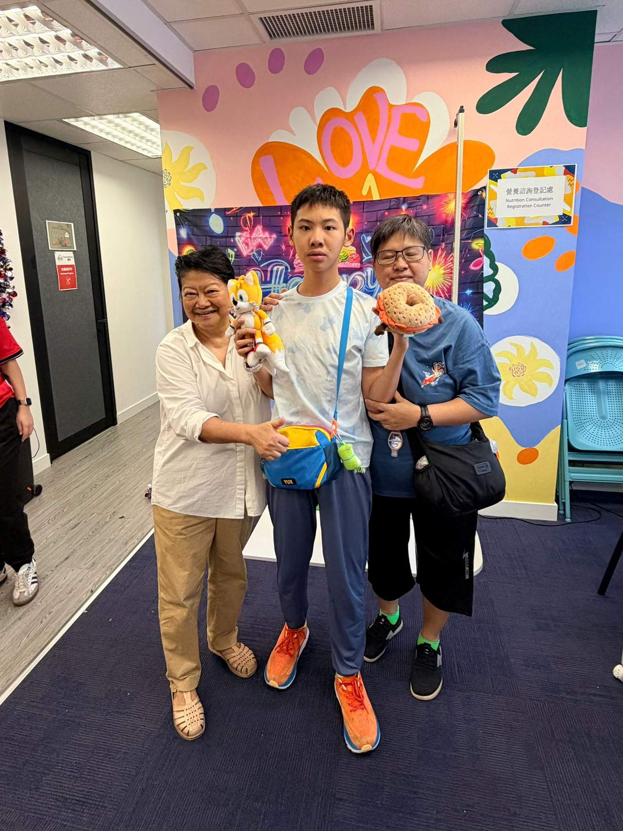 Three people pose together while displaying stuffed toys.