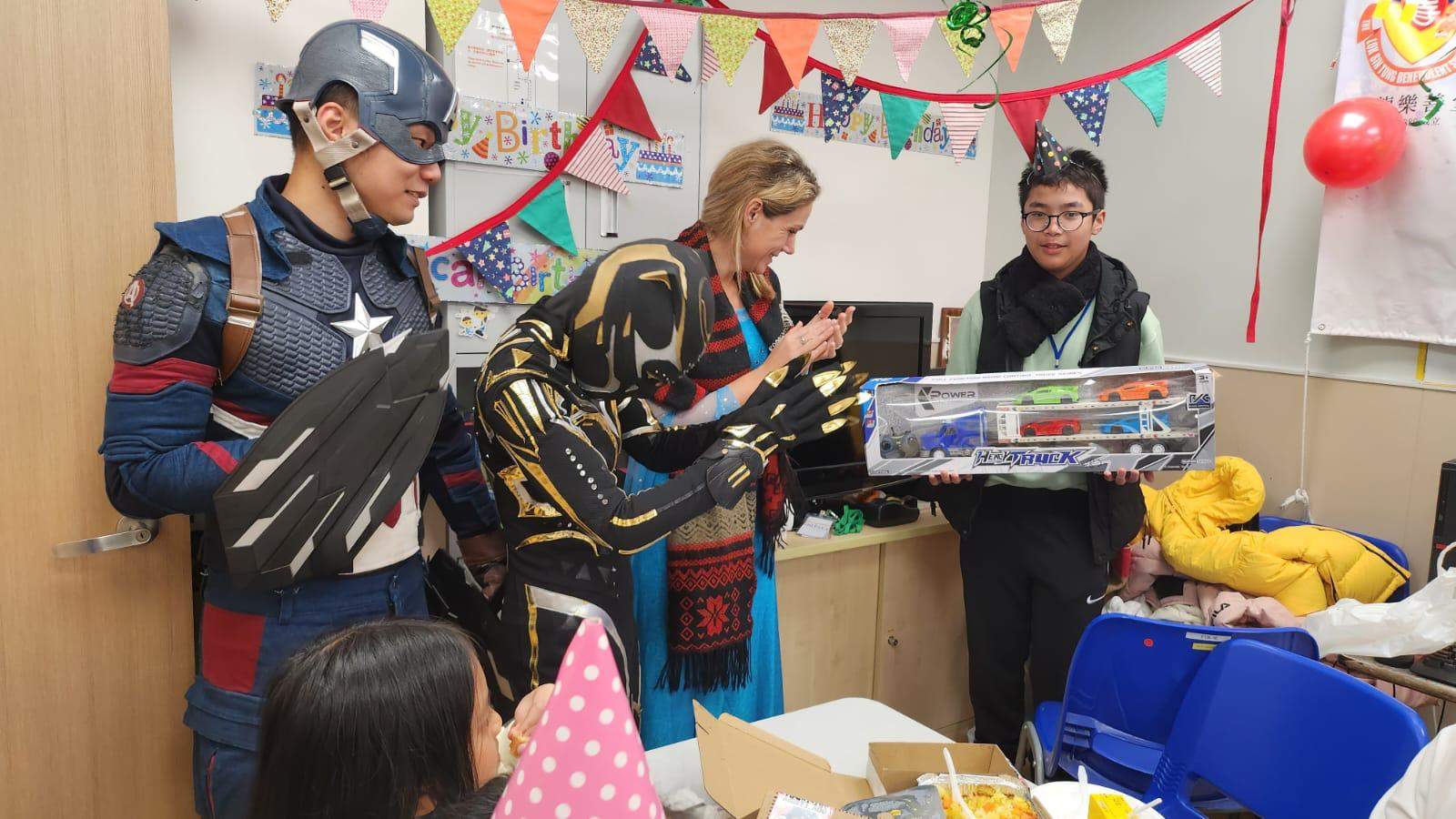 Costumed performers present a large boxed gift to a child.