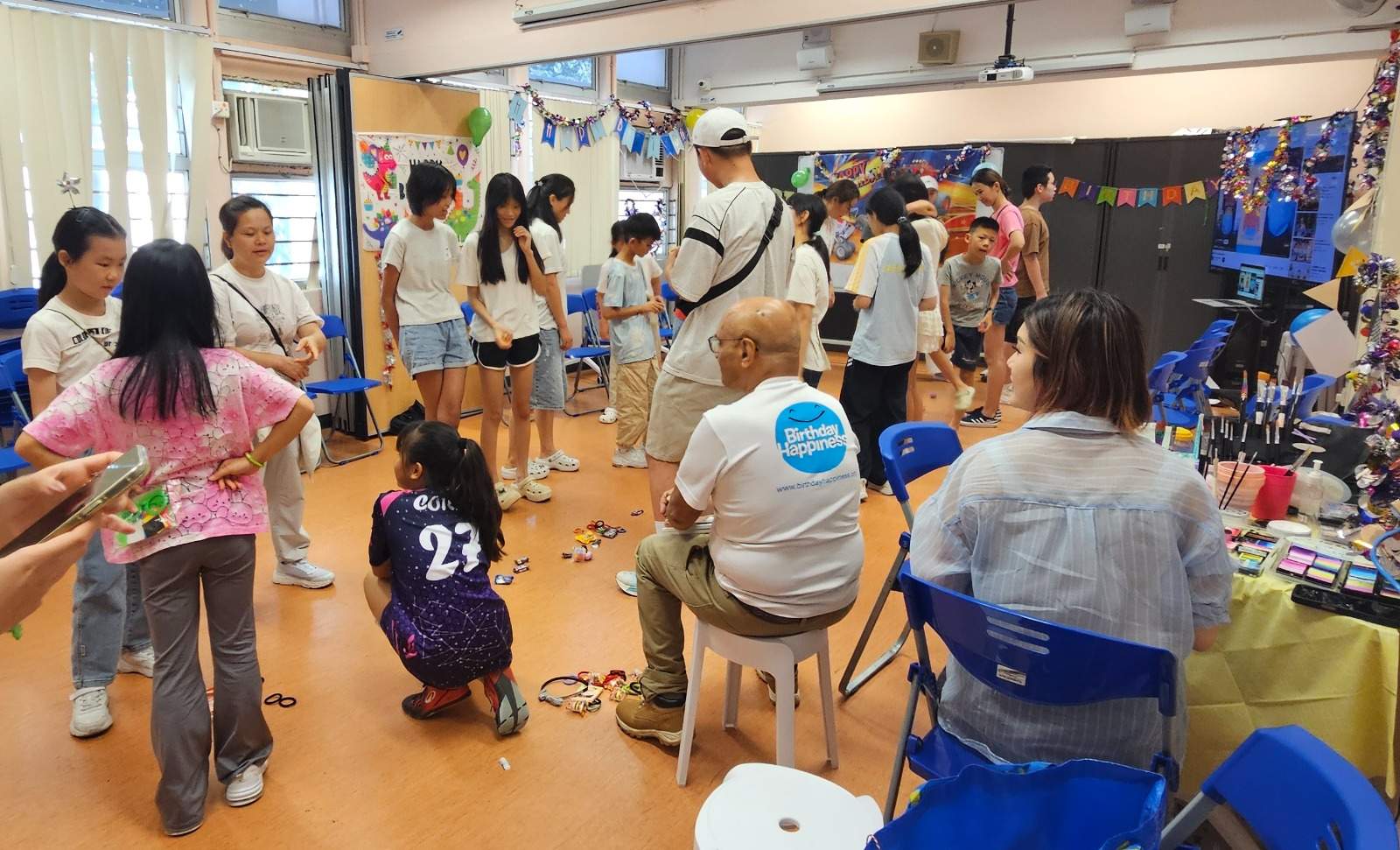 A group participates in an indoor activity among tables and chairs.